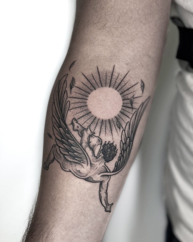Black and grey Icarus tattoo on the forearm, depiciting the mythological winged figure flying toward the sun with detailed shaing and fine line work. This Greek mythology-inspired tattoo symbolizes ambition, freedom and the consequences of overreaching. Perfect for those seeking meaningful mythological tattoos.