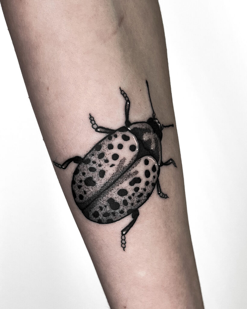 A bold black ink beetle tatoo placed on the forearm, featuring intricate shading and distinctive spotted patterns. This nature-inspired design is ideal for entomology enthusiats and anyone seeking a eye-catching bug or insect tattoo.